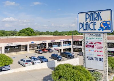 Storefronts and main pylon sign at Park Place Plaza, a shopping center in Azle TX