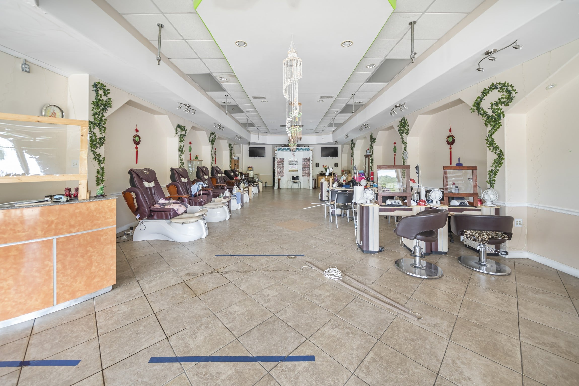 the interior view of the former nail salon at Marion City Square, with reception desk on the left followed by a line of chairs for foot services, and a row of tables and seating on the right for hand services, as a fully-furnished nail salon for lease