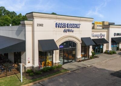 the Paris Banh Mi Cafe Bakery in Cordova TN, with black awnings and a covered patio with outdoor seating and a classy interior visible through the windows