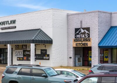 storefronts for Mita's Himalayan Kitchen and Outlaw Sporting Goods, facing a parking lot full of cars, in Columbus MS